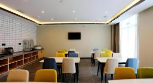 ein Esszimmer mit Tischen und Stühlen und einem Fernseher in der Unterkunft GreenTree Inn Express Jinan Zhangqiu Districty Ancinet Town Longquan Road in Zhangqiu