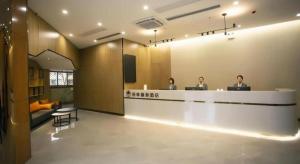 three people sitting at a reception desk in a lobby at GreenTree Inn Xiaoyi Wanda Plaza in Yaopu