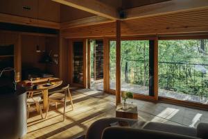 a living room with a table and a large window at SANU 2nd Home 北軽井沢 2nd in Kita-karuizawa