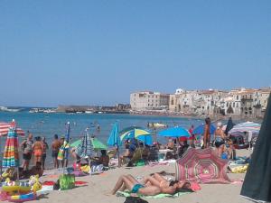 un gruppo di persone su una spiaggia con ombrelloni di Appartamento Seflonia a Cefalù