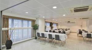 a banquet hall with white tables and chairs and windows at Caritas Oswald Cheung International House in Hong Kong
