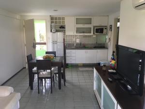 uma cozinha e sala de jantar com uma mesa e uma televisão em Ancorar Flat Resort 2207 B em Porto de Galinhas