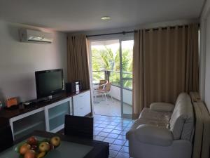 sala de estar con sofá y TV en Ancorar Flat Resort 2207 B en Porto De Galinhas