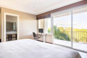 a bedroom with a bed and a desk and a balcony at Peninsula Langosta in Tamarindo