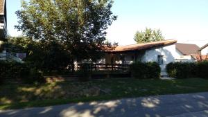 a white house with a fence and a tree at Rooms Lutra in Bilje