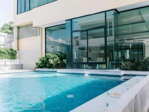 a house with a swimming pool in front of a building at Aramis Hotel in Nakhon Sawan
