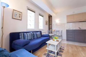 a living room with a blue couch and a kitchen at Tiffany Apartment in Ohrid
