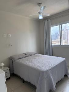 a bedroom with a bed and a ceiling fan at Ap 3 qtos 2vg gar cob Twice Guaruja in Guarujá +42 photos