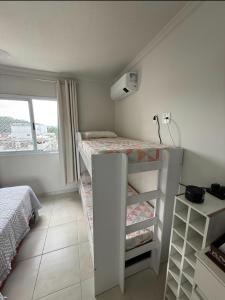 a small room with a bunk bed and a window at Ap 3 qtos 2vg gar cob Twice Guaruja in Guarujá