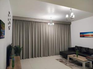- un salon avec un canapé et un grand rideau dans l'établissement Sifa Oasis, à Mascate