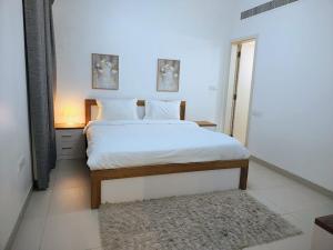 une chambre avec un lit blanc avec un tapis dans l'établissement Sifa Oasis, à Mascate