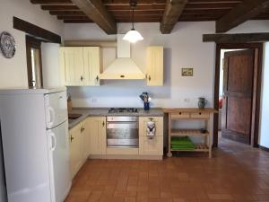 uma cozinha com armários brancos e um frigorífico branco em Casa Edera em Montelparo