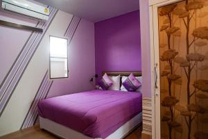 a purple bedroom with a bed with purple sheets and pillows at Palm Sweet Hotel in Sathani Rot Fai