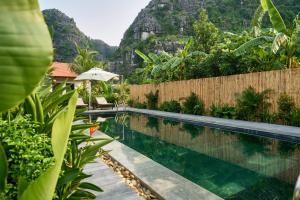 a swimming pool with a mountain in the background at The Greenary Garden in Ninh Binh