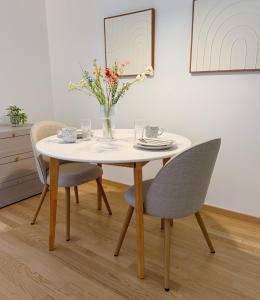une table avec des chaises et un vase de fleurs dessus dans l'établissement Suites am Herzogberg, à Brunn am Gebirge