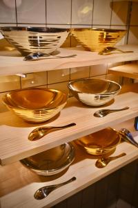 a shelf filled with gold bowls and spoons at ご当地ラーメン食べ放題 "The RAMEN HOTEL" -京都嵐山- in Kyoto