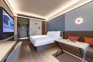 una camera d'albergo con un letto e una tv di Orange Hotel Shanghai Meilong Wanhui International Plaza a Shanghai