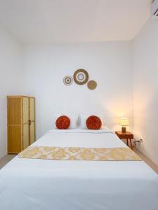 ein weißes Schlafzimmer mit einem weißen Bett und einer Uhr an der Wand in der Unterkunft Yan Loft in Uluwatu