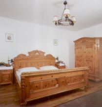 a bedroom with a wooden bed and a chandelier at Hotel Schwarzes Rössl in Salzburg