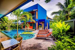 a blue building with chairs and a swimming pool at OYO 422 Jane Homestay and Resort in Ban Kata