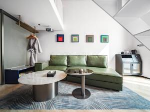 a living room with a green couch and a table at Chenfeng Hotel Wuhan Baishazhou Longhu Tianjie Branch in Wuhan
