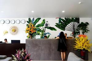 a woman standing at a counter in a room with plants at Green Oasis Hotel in Phường Sáu