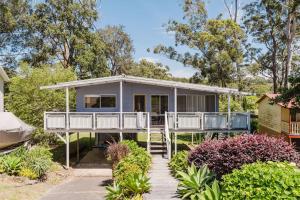 a house with a wrap around porch in a garden at Medona - Narrawallee Beach House in Narrawallee