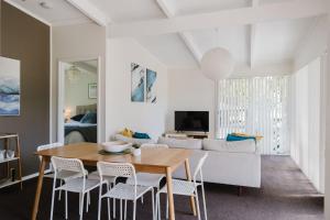 a living room with a table and chairs and a couch at Medona - Narrawallee Beach House in Narrawallee