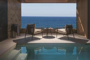 a patio with two chairs and a table and the ocean at Hilton Chania Old Town Resort & Spa in Chania