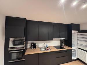 La cuisine est équipée de placards noirs, d'un évier et d'un four micro-ondes. dans l'établissement Möbliertes Familienhaus in Hamburg, à Niederdorla 11 autres photos