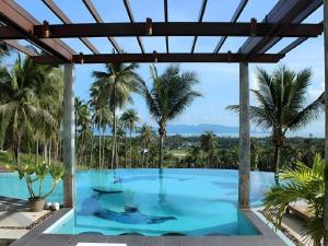 ein Swimmingpool mit Palmen im Hintergrund in der Unterkunft Grand Hill Residence in Ban Tai