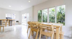 a dining room with a table and chairs and windows at Maximize Brand New Hostel Udonthani in Udon Thani