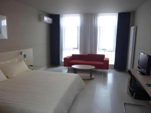 ein Hotelzimmer mit einem Bett und einer roten Couch in der Unterkunft Jinjiang Inn Yantai Penglaige Zhonglou North Road in Penglai