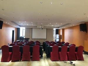 a conference room with red chairs and a white screen at Jinjiang Metropolo Hotel - Liyang Tianmu Lake in Liyang