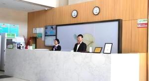 two people sitting at a counter in an airport at GreenTree Inn Express Laizhou Bus Station Wenhua Xi Street in Laizhou