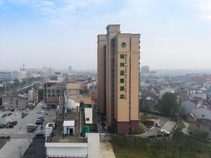 JiulianにあるGreenTree Inn Maanshan Hanshan District Jiuwu Square Hotelの市時計塔のある高層ビル