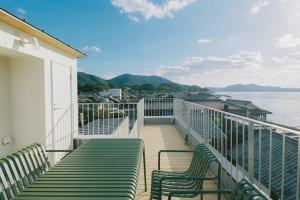 a balcony with green benches and a view of the water at SOIL Setoda in Onomichi