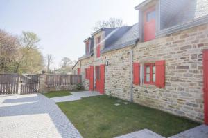 una casa de ladrillo con puertas rojas y un patio en Le pressoir, en Guidel