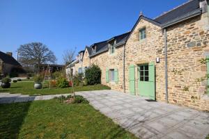 un edificio de ladrillo con una puerta verde en un patio en L'oree des mers, en Guidel