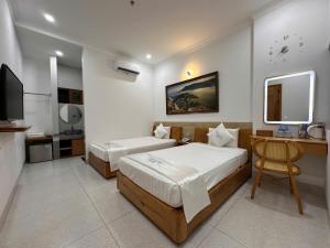 a bedroom with two beds and a desk and a television at HOLIDAY HOTEL PHAN THiẾT in Ấp Bình Hưng