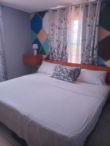 a bed with white sheets and pillows in a bedroom at Love Den in Christ Church