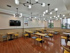 a restaurant with tables and chairs and a flat screen tv at GreenTree Inn Ganzhou Gan County Bus Station in Meilin