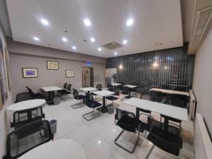 ein großes Zimmer mit Tischen und Stühlen in einem Restaurant in der Unterkunft Jinjiang Inn Qingdao International Exhibition Center Haier Road in Qingdao