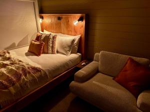 a bedroom with a bed and a couch and a chair at The Tiny Apostle - Great Ocean Road in Princetown