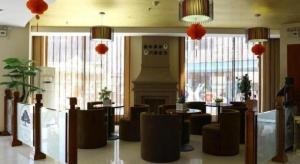 a restaurant with tables and chairs and a fireplace at GreenTree Inn Taicang Baolong Square Hotel in Taicang