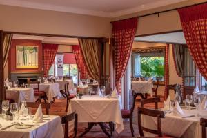 a dining room with white tables and chairs at Kensington Lodge Golf Estate Villa - 17 Pinehurst Drive in White River