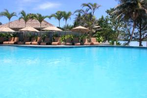 a large swimming pool with chairs and umbrellas at Nautilus Resort in Rarotonga
