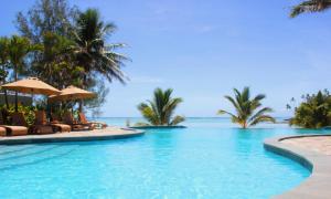 uma piscina com cadeiras e palmeiras e o oceano em Nautilus Resort em Rarotonga