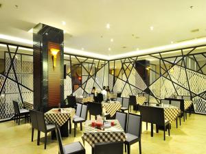 ein Restaurant mit Tischen und Stühlen und Menschen im Hintergrund in der Unterkunft Qionghai Jin Mao Hotel in Qionghai