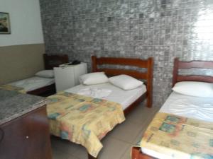 a room with two beds in a room with a counter at Barrocos Hotel in Rondonópolis